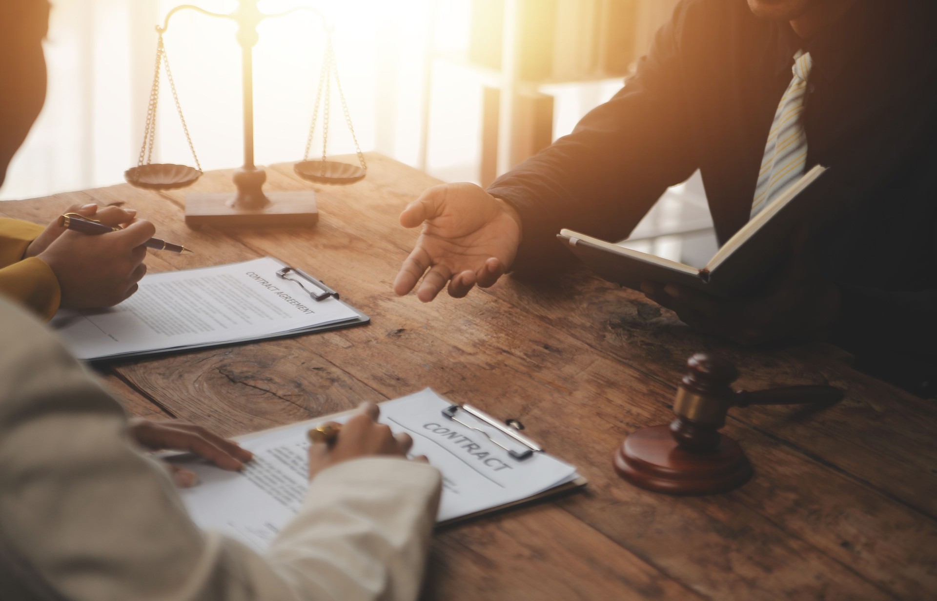 Business and lawyers discussing contract papers with brass scale on desk in office. Law, legal services, advice, justice and law concept picture with film grain effect